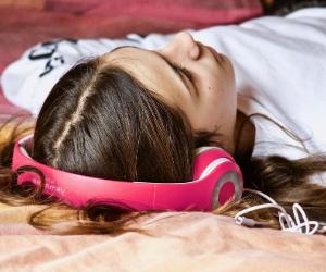 A teenage giril is on bed with headphone